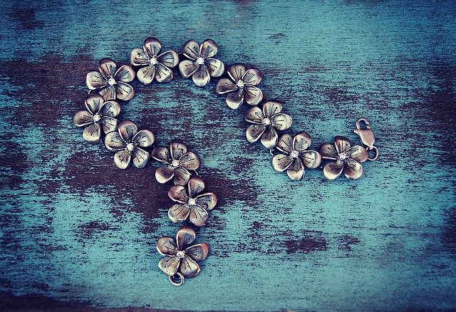 Strieborný náhrdelník z kvetou s patinou na modrom stole.jpg